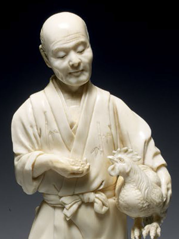 Ivory okimono of a man holding a cockerel